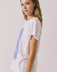 Side view of woman wearing Chaser’s white Guns N’ Roses World Tour Tee with colorful tour graphic (licensed band collaboration) on a plain background