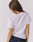 Back view of a woman wearing Chaser's white Golden Hour Tee on a plain background
