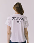 Back view of a woman wearing Chaser's white Journey 1980 Tour Tee with Japan 81 text on a plain background