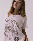 Side view of a woman wearing Chaser's the Grateful Dead 60 Years so Far pink tee with a graphic design on a plain background