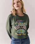 Front view of womens wearing Chaser's Classics Motors washed bronze green long sleeve with retro graphic on a plain background