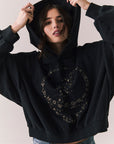 Front view of The Grateful Dead We Are Everywhere Hoodie in True Black with cropped boxy fit, hood up, and skull graphic made from stars and zodiac signs against a plain background