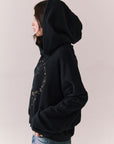 Side view of The Grateful Dead We Are Everywhere Hoodie in True Black with cropped boxy fit, hood up, and skull graphic made from stars and zodiac signs against a plain background