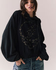 Side view of The Grateful Dead We Are Everywhere Hoodie in True Black with cropped boxy fit and skull graphic made from stars and zodiac signs against a plain background