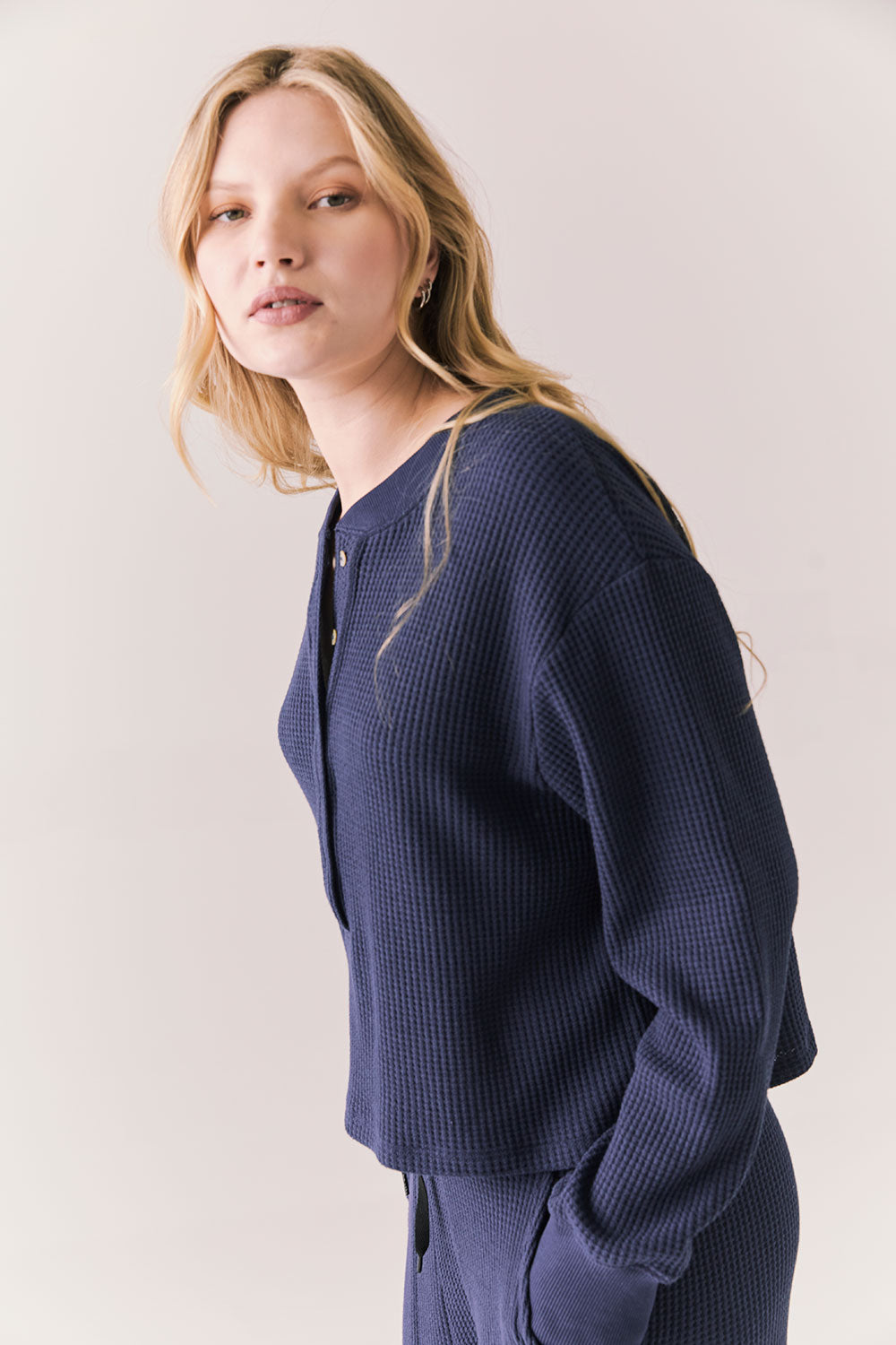 Side view of Thayne cropped thermal henley top in Midnight Blue with 3/4 button placket and ribbed texture against a plain background