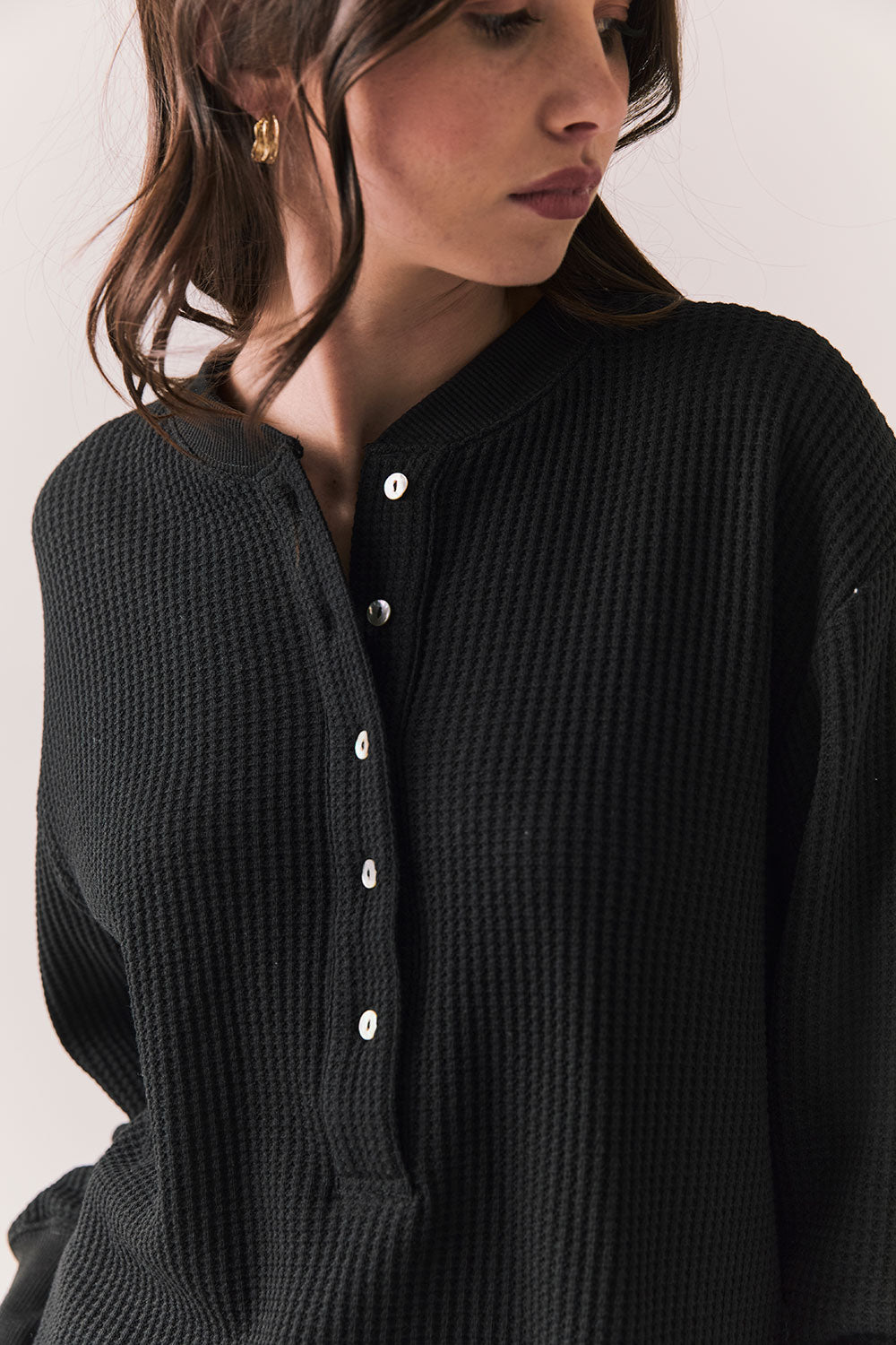 Closeup front view of Thayne Long Sleeve in True Black with cropped fit, henley placket, and ribbed texture against a plain background