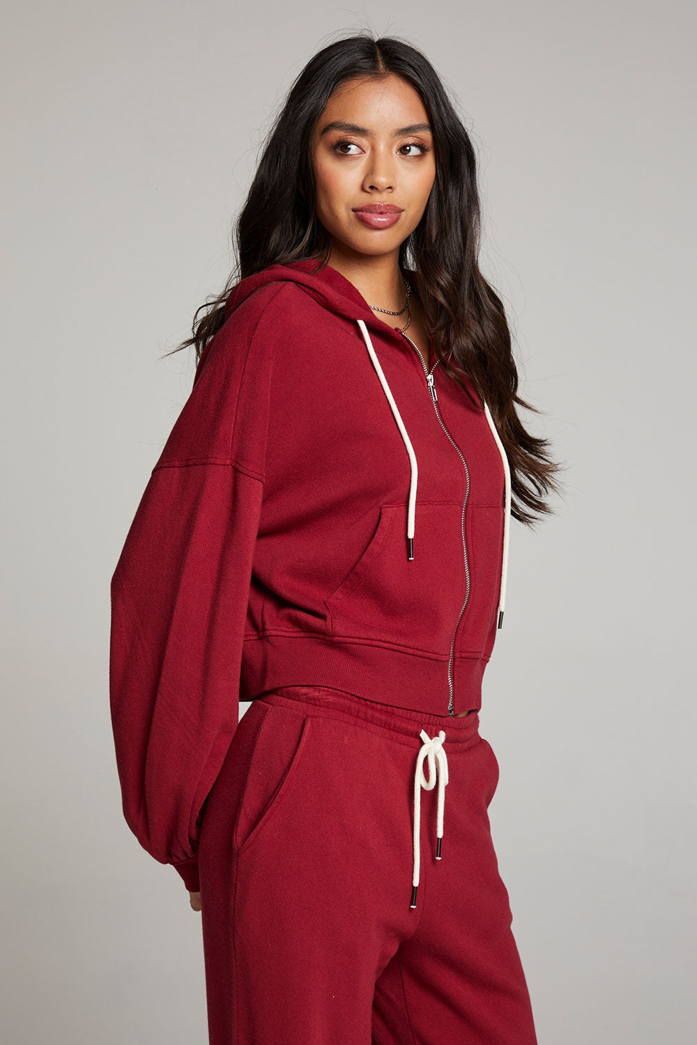 Side view of model wearing Abilenee Blood Red Zip Up Hoodie with cropped hem and full-zip closure against a plain background