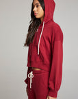 Side view of model wearing Abilenee Blood Red Zip Up Hoodie with cropped hem and hoodie up and full-zip closure against a plain background