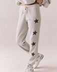 Side view of NYC Stars Joggers in Heather Grey with black star print down each leg, styled for a casual lounge look, against a plain background