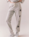 Side view of NYC Stars Joggers in Heather Grey with black star print down each leg, styled for a casual lounge look, against a plain background