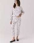 Full body view of woman wearing Chaser’s Festive Stars Joggers in light grey with star patterns and matching top on a white background