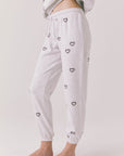 Side view of woman wearing Chaser’s light grey Tossed Hearts Pants with small heart patterns on a white background
