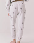 Back view of woman wearing Chaser’s light grey Tossed Hearts Pants with small heart patterns on a white background