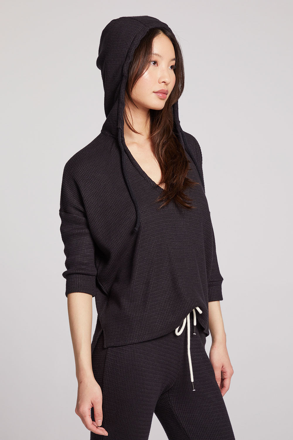 Side view of model wearing 3/4 Sleeve Split Side Licorice Dolman Hoodie in black showing relaxed fit and split-side detail on plain background and the hoodie up