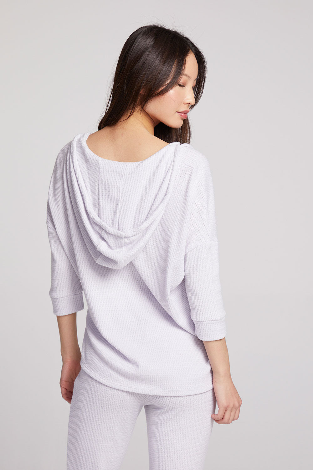 Back view of model wearing 3/4 Sleeve Split Side Light Heather Grey Dolman Hoodie with dolman sleeves and split-side hem on plain background with matching joggers