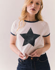Woman wearing a white t-shirt with a black star design on a plain background