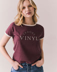 Front view of model in J’adore Vinyl Tee in fig purple with cream ringer trim and vintage-style text