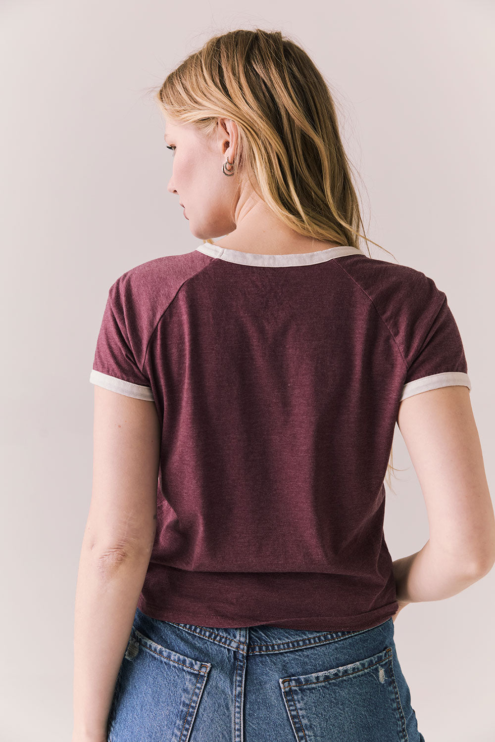 Back view of model in J’adore Vinyl Tee in fig purple with cream ringer trim and vintage-style text