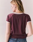 Back view of model in J’adore Vinyl Tee in fig purple with cream ringer trim and vintage-style text