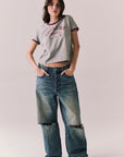 Full body view of model in Coca-Cola heather grey ringer tee and denim