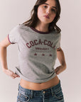 Woman wearing a gray 'Coca-Cola University' t-shirt against a plain background