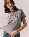 Woman wearing a gray 'Coca-Cola University' t-shirt with red text on a plain background