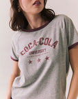 Woman wearing a gray 'Coca-Cola University' t-shirt with red accents.