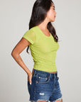 Side view of model wearing the 90’s Chartreuse Baby Tee in bright green with scoop neck and fitted cropped cut and cut off denim against a plain background