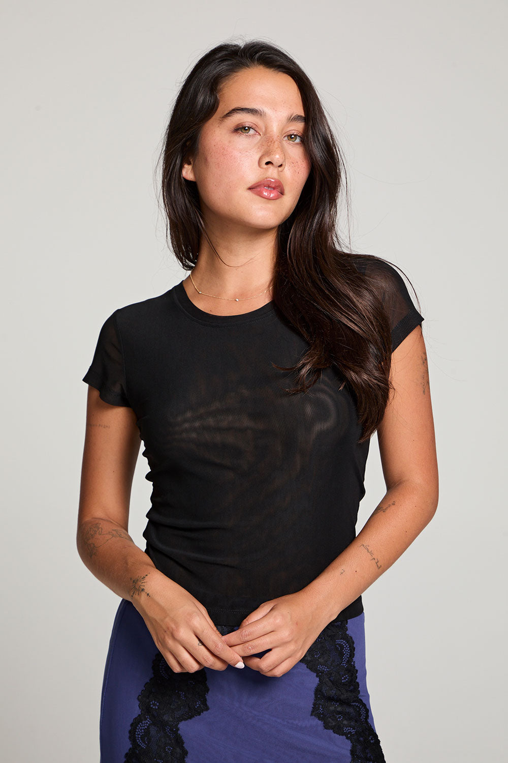 Front view of model wearing 90’s Licorice Black Baby Tee with scoop neckline and fitted waist with a purple skirt with black lace against a plain background