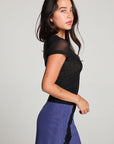 Side view of model wearing 90’s Licorice Black Baby Tee with scoop neckline and fitted waist with a purple skirt against a plain background