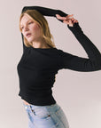 True black fitted ribbed long sleeve top with thumb holes and minimalist silhouette.