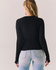 True black fitted ribbed long sleeve top with thumb holes and minimalist silhouette.