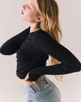 True black fitted ribbed long sleeve top with thumb holes and minimalist silhouette.