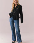 Full front view of a model wearing the Helenaa button-down shirt in True Black with collared neckline and oversized silhouette, styled with relaxed jeans against a plain backdrop.