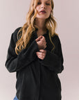 Front view of a model wearing the Helenaa button-down shirt in True Black with collared neckline and oversized silhouette, styled with relaxed jeans against a plain backdrop.