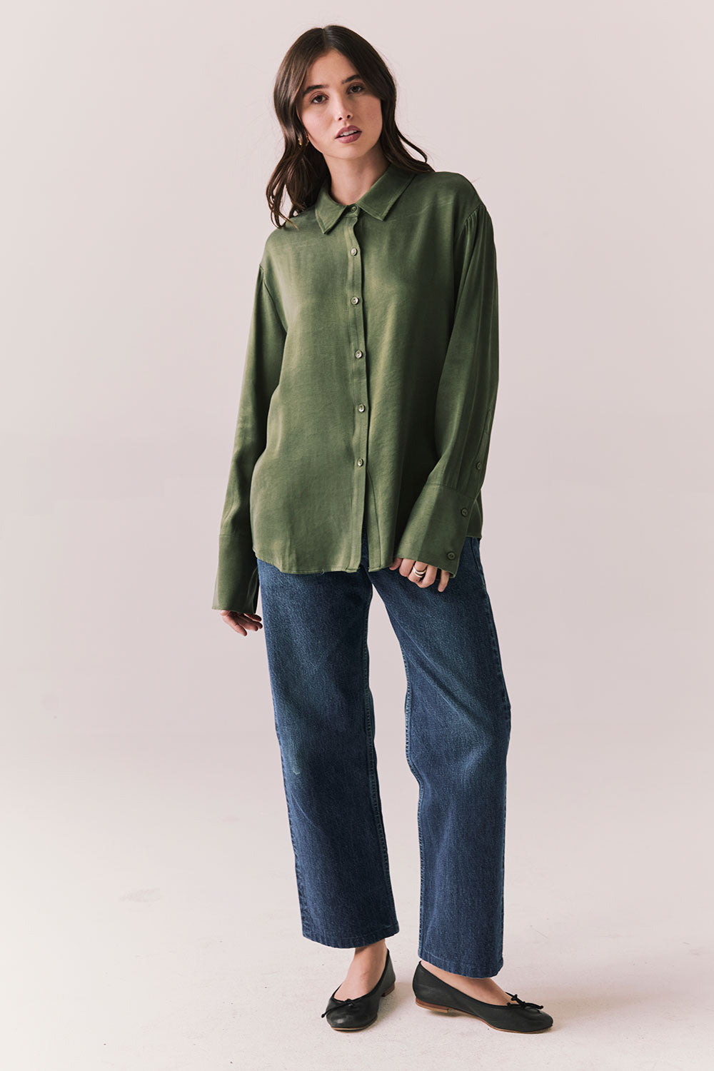 Full front view of a model wearing the Helenaa button-down shirt in bronze green with collared neckline and relaxed silhouette, styled with blue jeans, against a plain background.