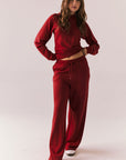 Full body look of model wearing Sandyy Crimson Red Trousers with coordinating hoodie.