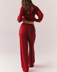 Full body back look of model wearing Sandyy Crimson Red Trousers with coordinating hoodie.