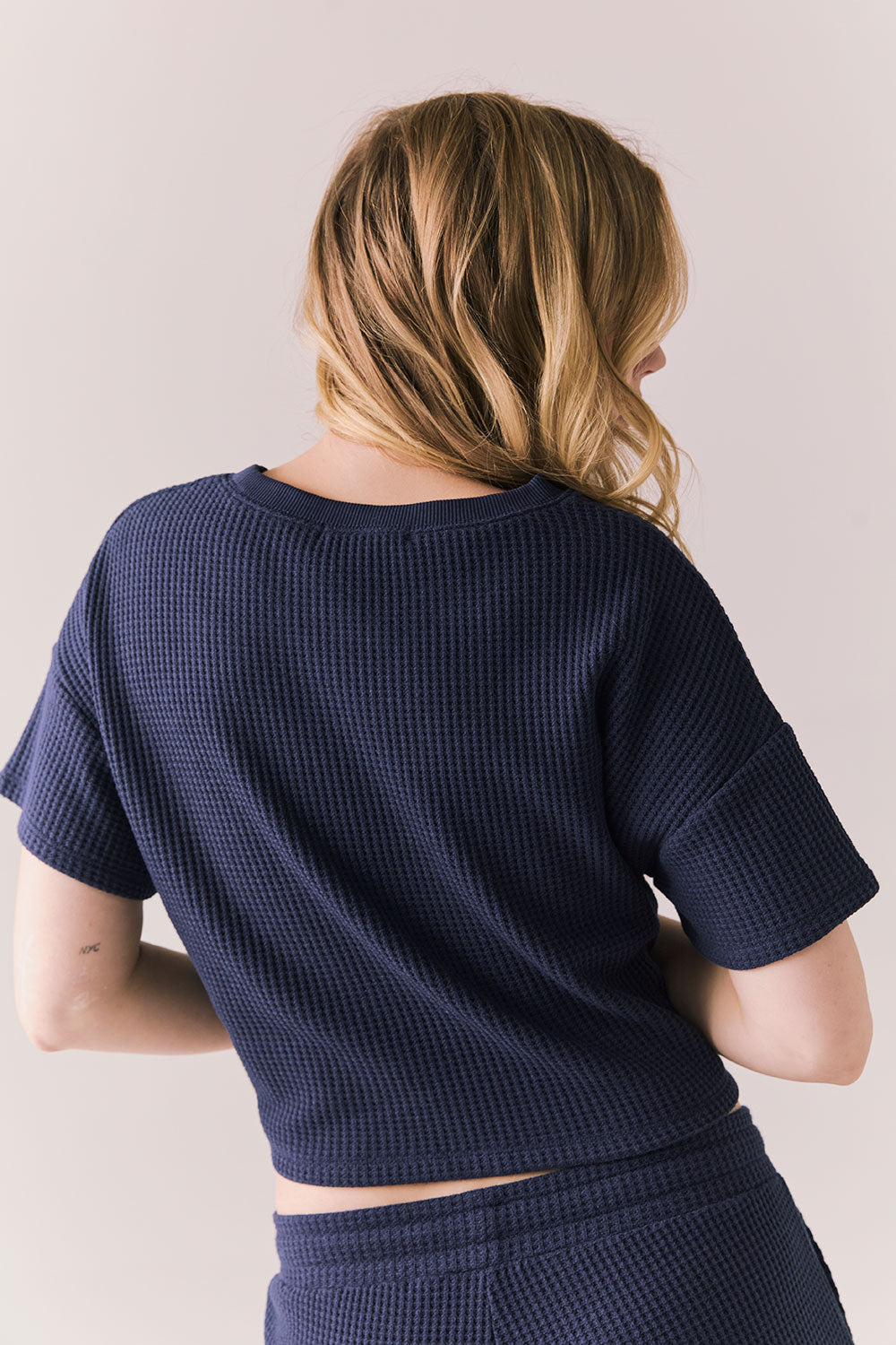 Back view of model in Irvine Tee in midnight blue with soft thermal texture on plain background