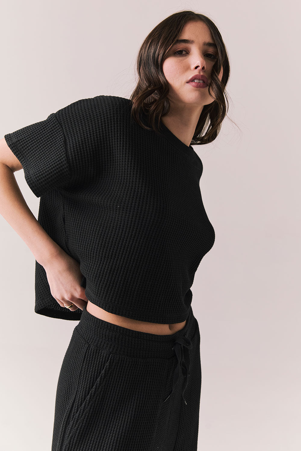 Side view of model in Irvine Tee in true black with soft thermal texture on plain background