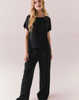 Full front view of woman wearing Davis tee in true black and matching Lee Pant against a plain background