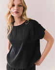 Side view of woman wearing Davis tee in true black and matching Lee Pant against a plain background