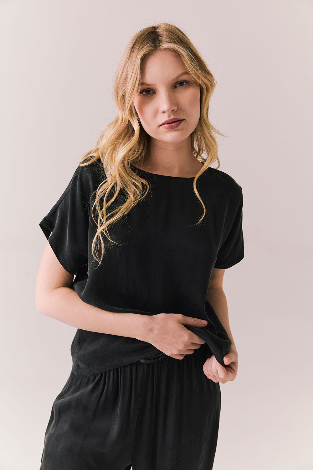 Front view of woman wearing Davis tee in true black and matching Lee Pant against a plain background