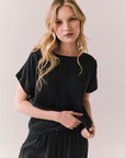Front view of woman wearing Davis tee in true black and matching Lee Pant against a plain background