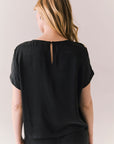 Back view of woman wearing Davis tee in true black and matching Lee Pant against a plain background