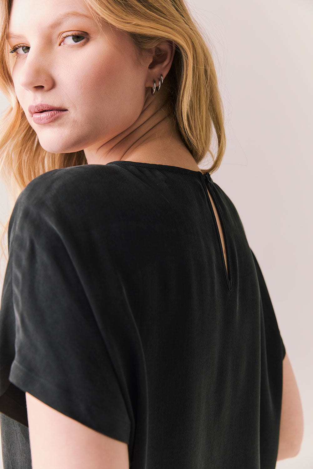 Back view of woman wearing Davis tee in true black and matching Lee Pant against a plain background