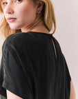 Back view of woman wearing Davis tee in true black and matching Lee Pant against a plain background