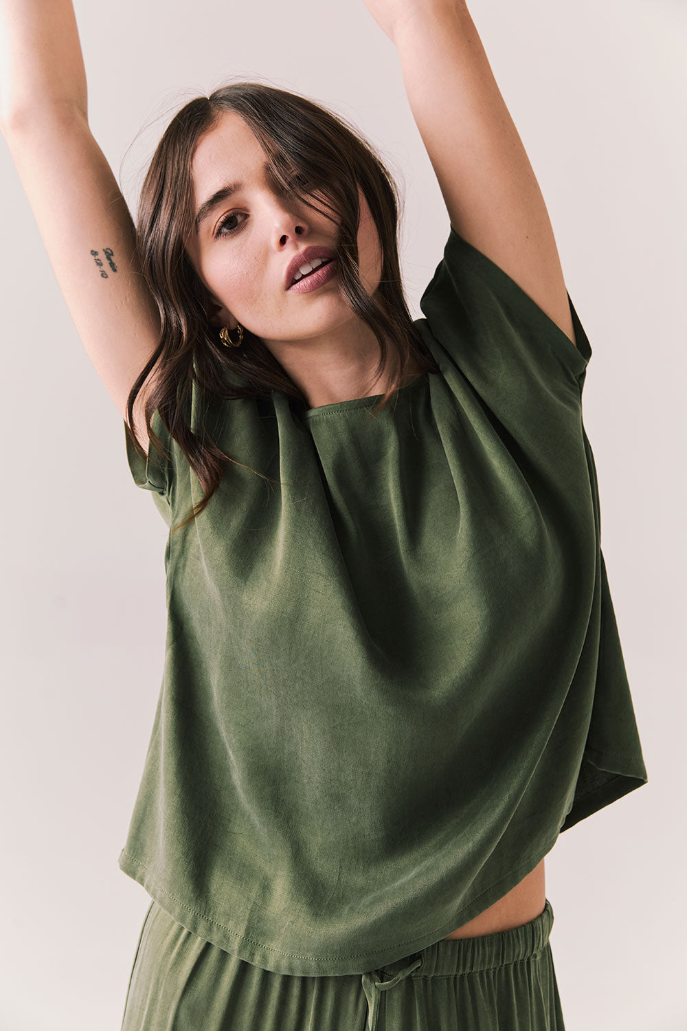 Woman wearing the Davis tee in bronze green against a plain background