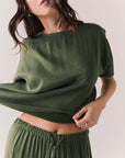 Front view of woman wearing the Davis tee in bronze green with matching Lee trousers, shot on a white background.