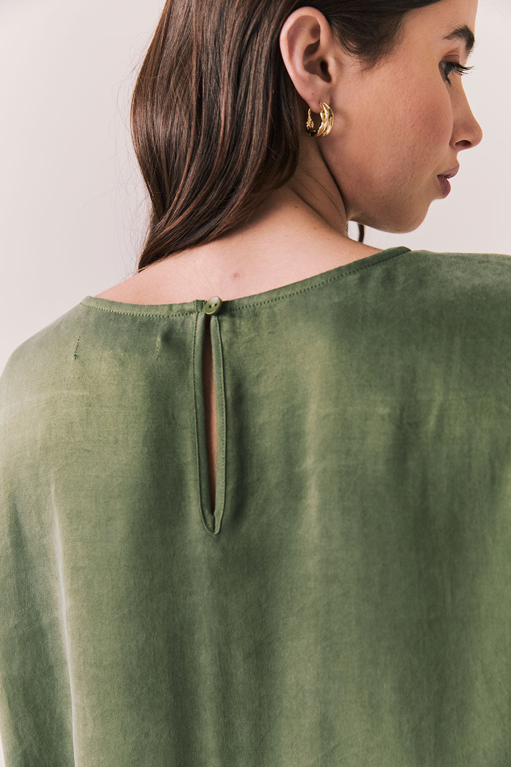 Back view of woman wearing the Davis tee in bronze green with matching Lee trousers, shot on a white background.
